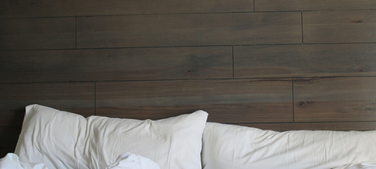A bed with a used mattress, blanket and pillows