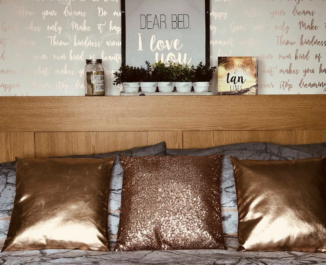 A wooden bed frame, three golden pillows, and a bed sheet.