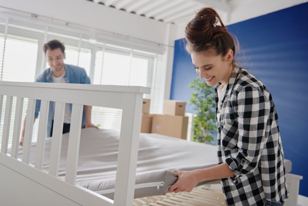 Couple putting mattress on the bed.