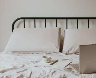A bed with a black metal frame, soft bedding, and a laptop on the bed, perfect for small living spaces